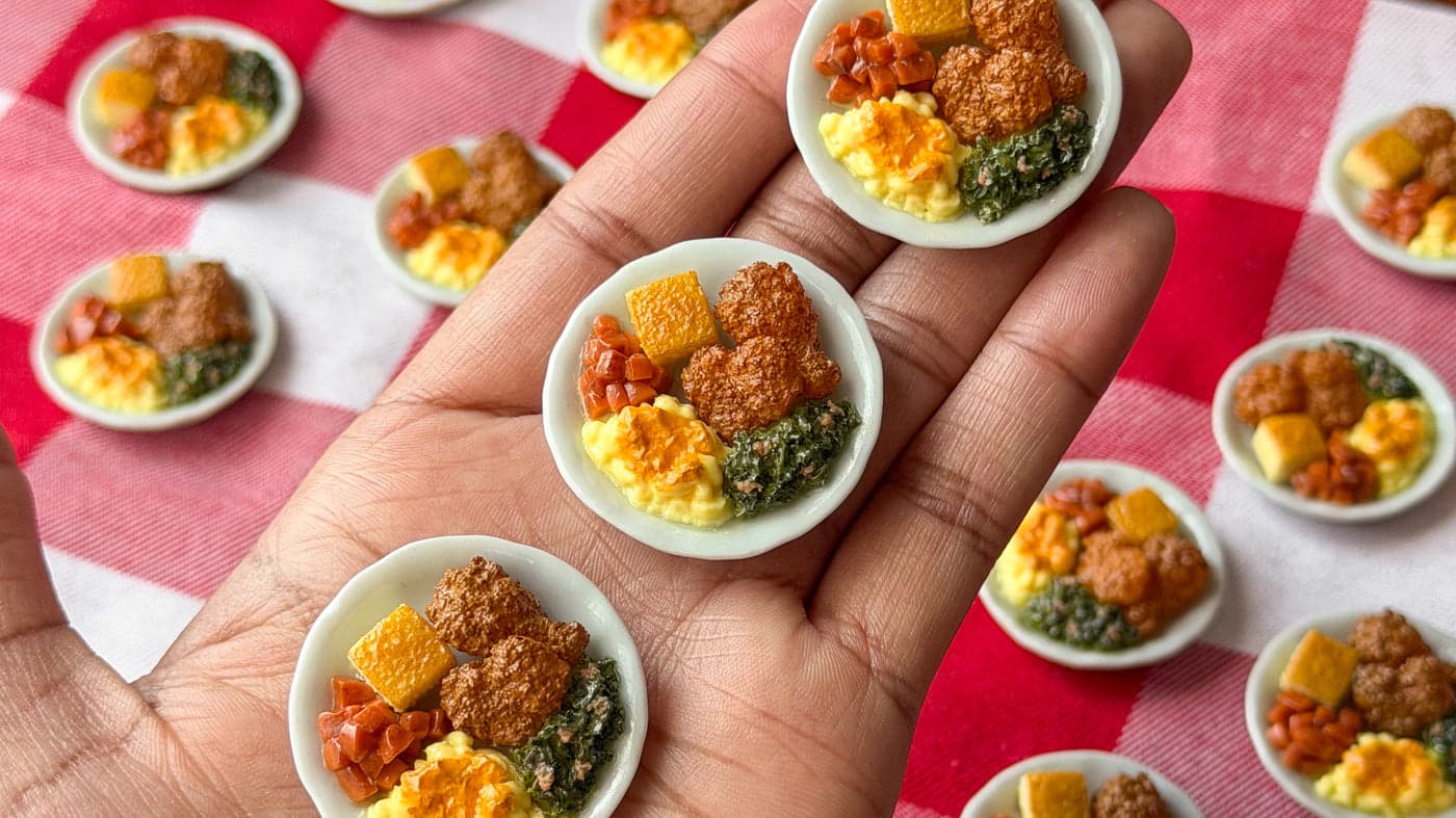 Tiny handmade soul food plates held in the artist's hand